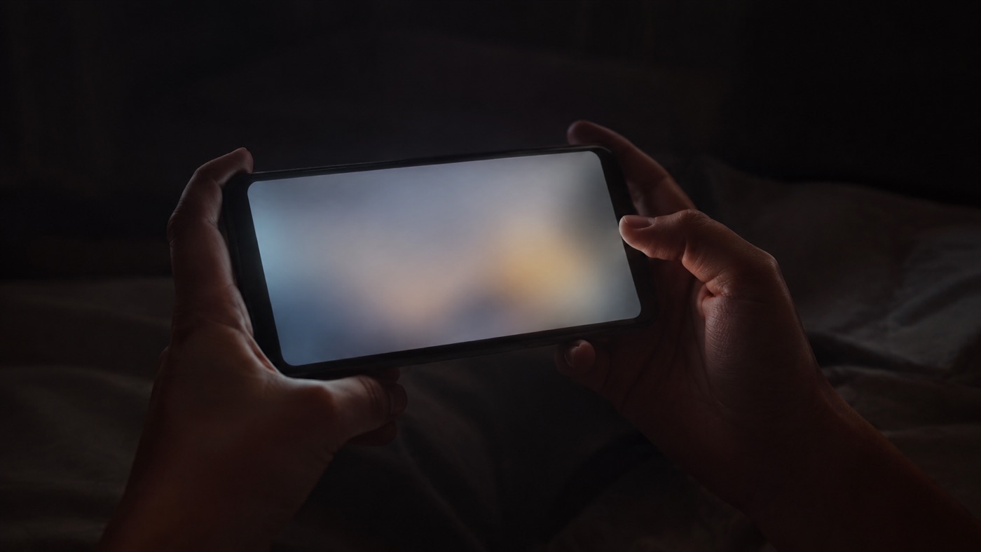 夜、スマートフォンで動画を見ている手元